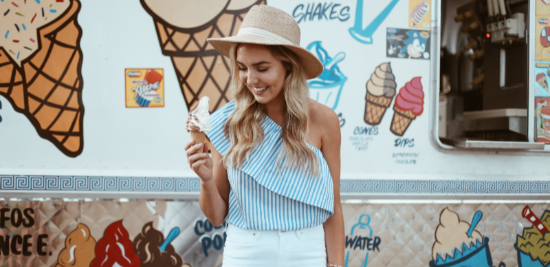 Junge Frau mit Sonnenhut isst Eiscreme