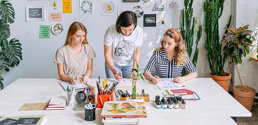 Drei Menschen arbeiten gemeinsam an einem Tisch